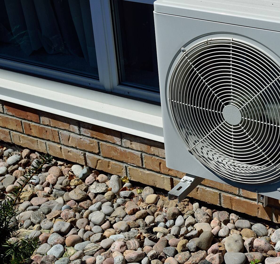 Outdoor air conditioning unit beside a brick house