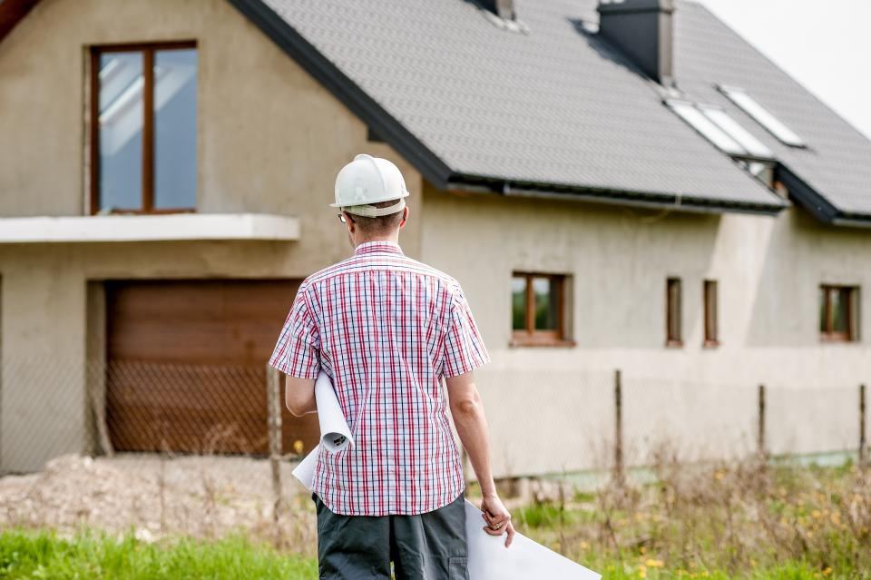 Builder in a hard hat looking at a new house